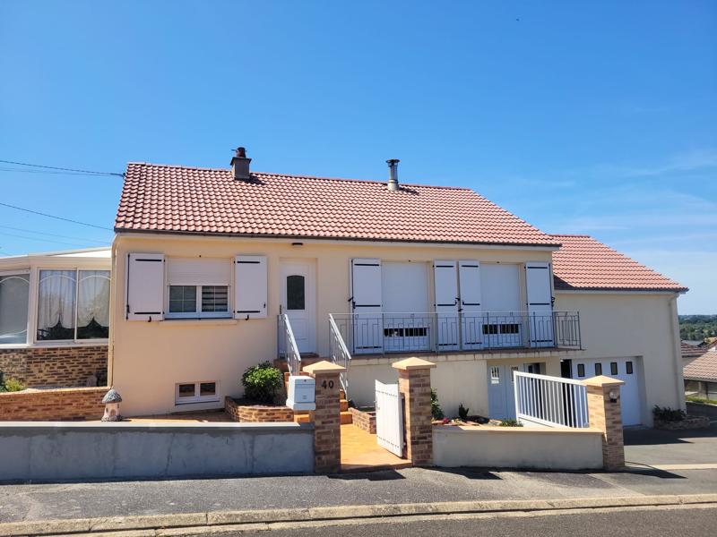 Maison de style pavillon peinte en jaune pâle avec un toit de tuiles rouges et des volets blancs.