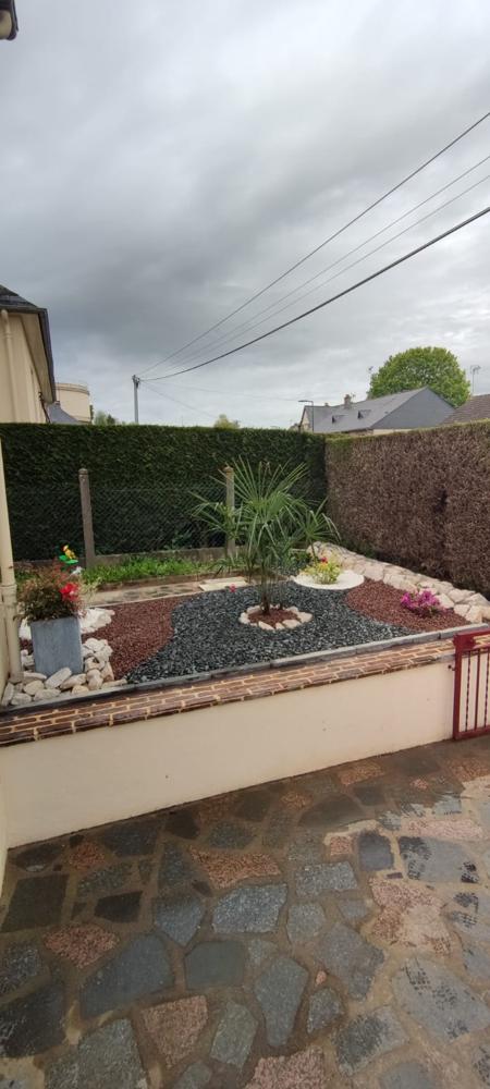 Aménagement paysager avec palmier et graviers décoratifs devant un mur avec isolation thermique par l'extérieur