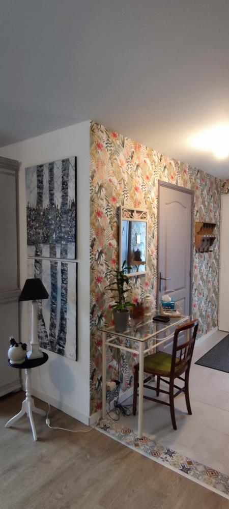 Salon décoré avec papier peint tropical multicolore, mobilier vintage et tableaux d'art