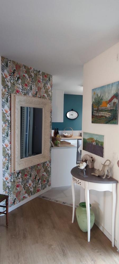 Autre angle du salon tropical avec papier peint jungle, console vitrée et décoration artistique