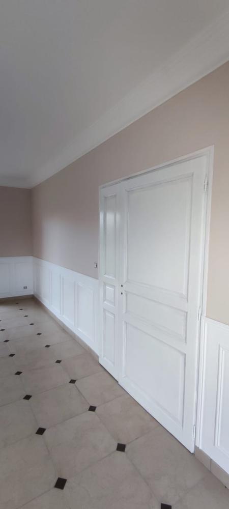 Chambre avec lambris blancs style classique, murs beige rosé et porte blanche traditionnelle