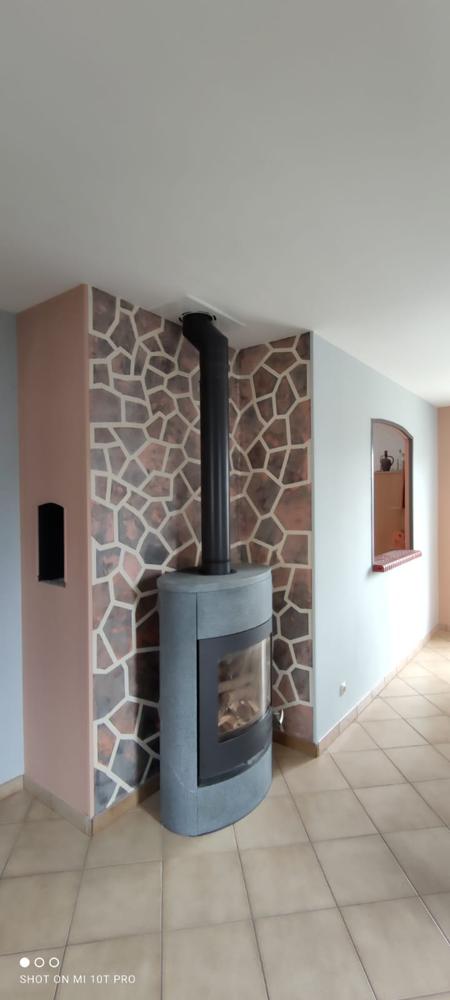 Salon avec cheminée moderne, mur décoratif effet pierre multicolore et carrelage beige