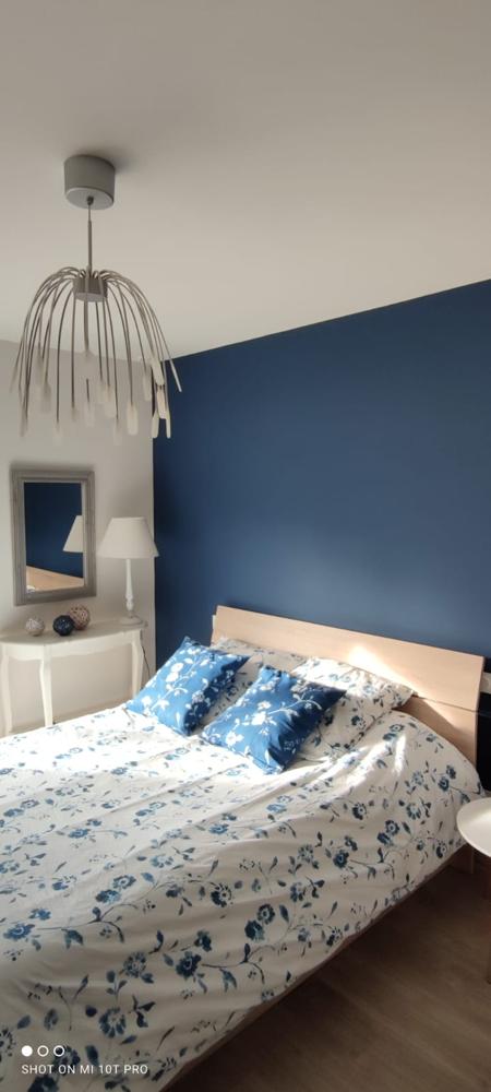 Chambre cosy avec mur bleu marine, luminaire design et linge de lit à motifs floraux