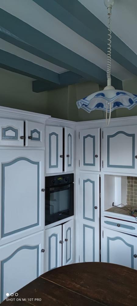 Cuisine traditionnelle avec poutres vert canard, meubles blancs à liserés verts et luminaire rustique