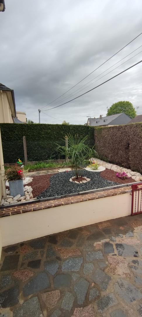 Aménagement paysager avec palmier et graviers décoratifs devant un mur avec isolation thermique par l'extérieur