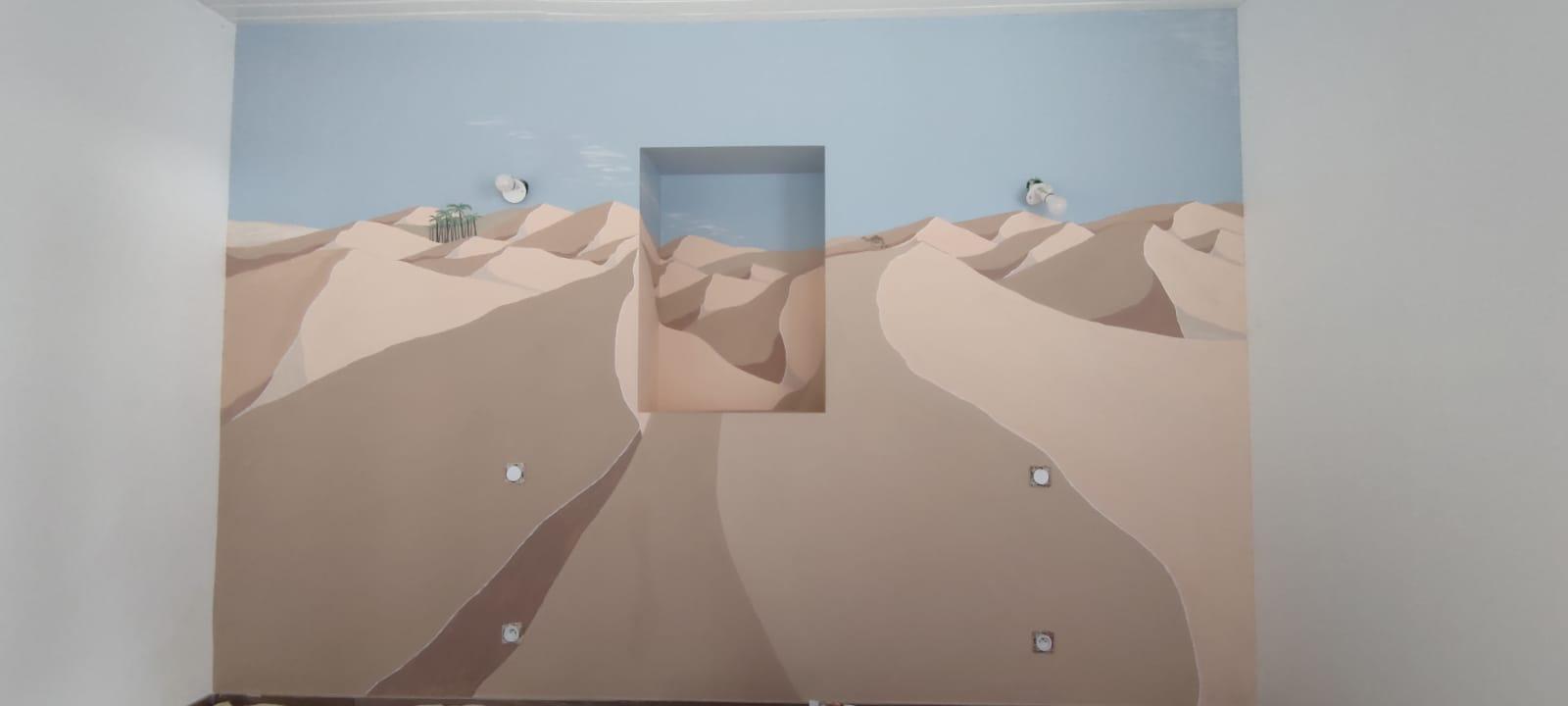 Fresque murale représentant un paysage désertique avec dunes beiges et ciel bleu, avec fenêtre encastrée