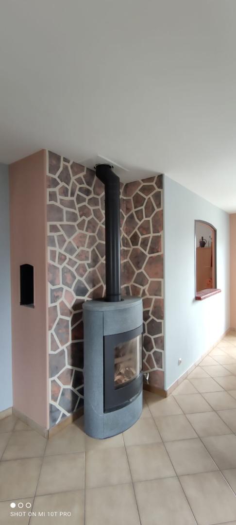 Salon avec cheminée moderne, mur décoratif effet pierre multicolore et carrelage beige