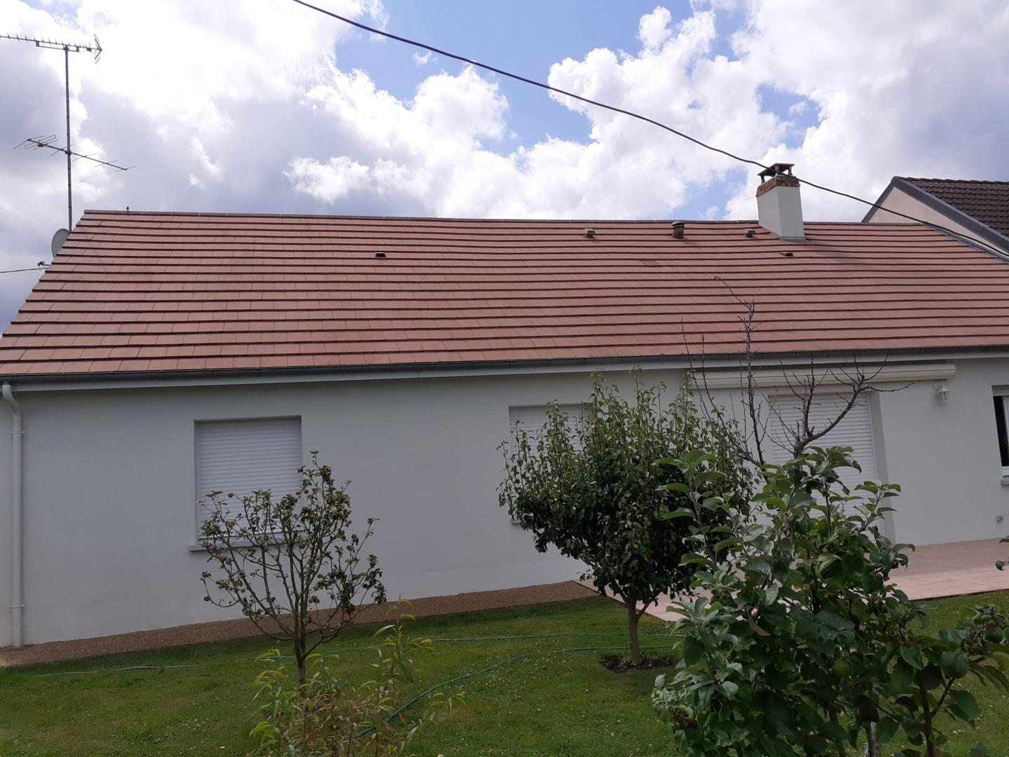 Toiture en tuiles rouges entièrement rénovée sur une maison blanche.