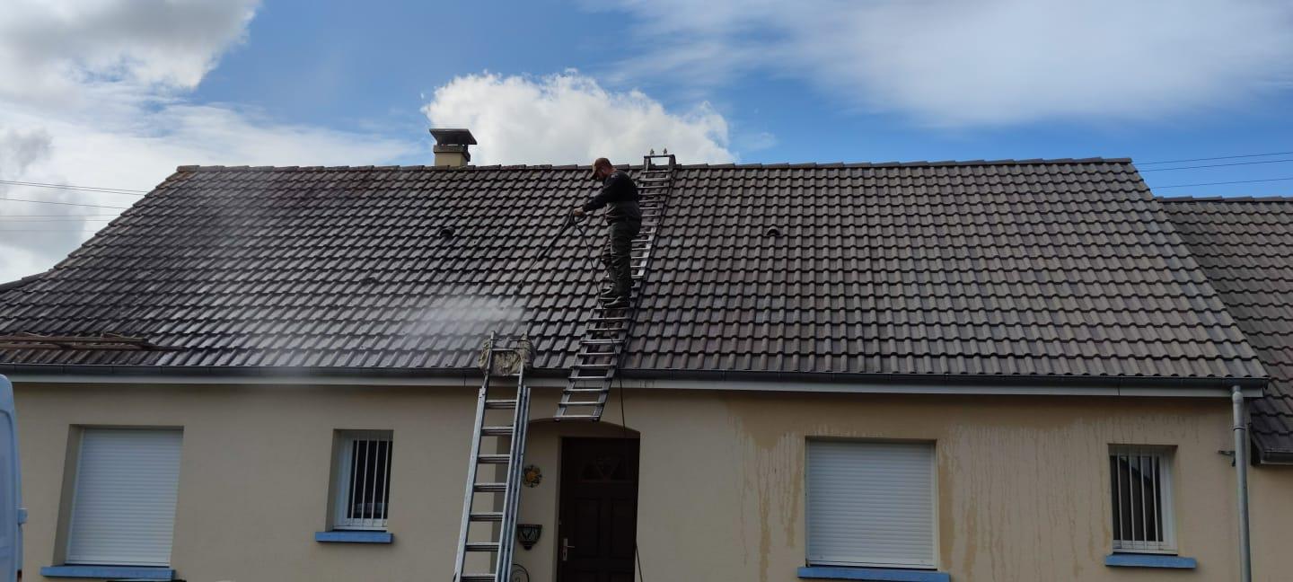 Nettoyage d'une toiture en tuiles foncées par un professionnel équipé.